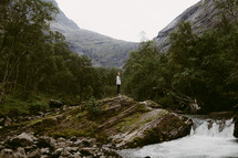 a woman standing near a waterfall 