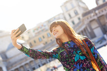 young woman with red hair and freckles takes a selfie in Piazza Pebliscito in Naples.