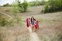 woman walking up a hill wrapped in a blanket 