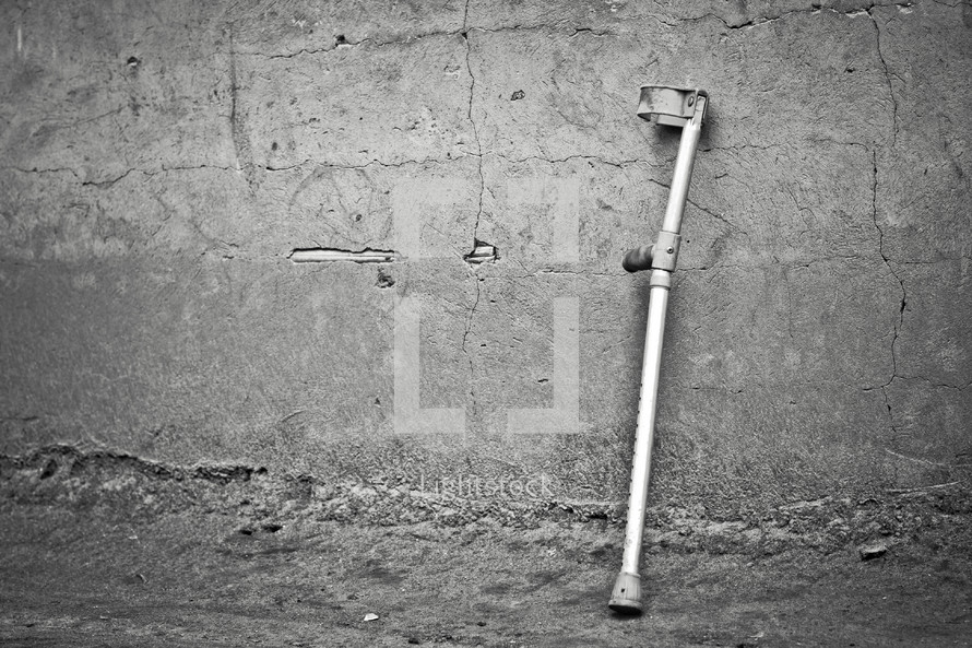 A crutch resting against a concrete wall