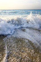 Ocean waves crashing onto the beach sand.