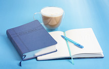A Holy Bible with a Notebook to Study on a blue Background