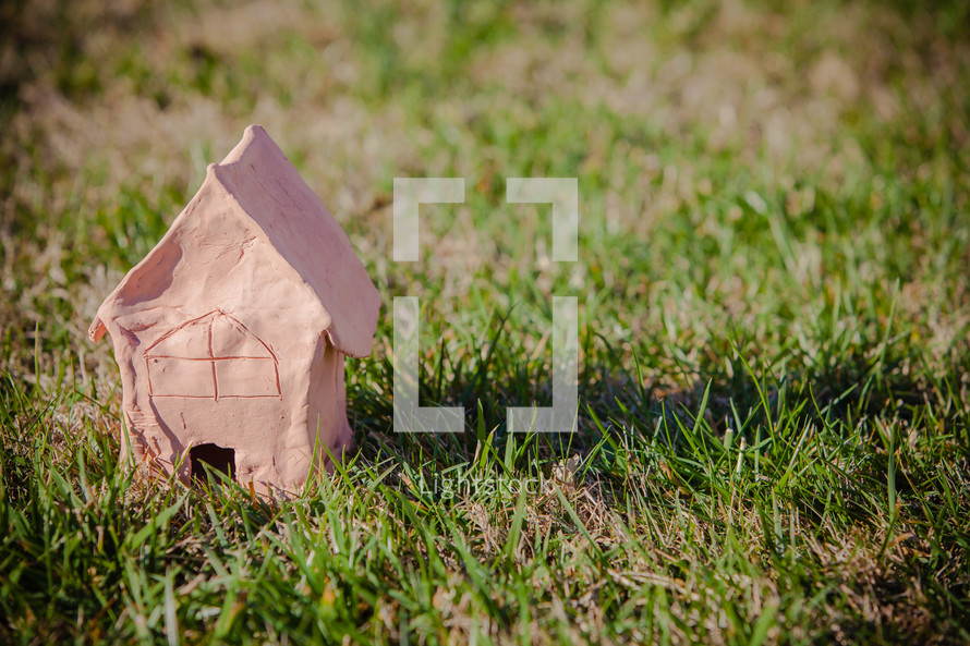 Handmade clay model of a home in the grass; day, outdoors, sun setting; As for me and my house, we will serve the Lord  (Joshua 24:15)