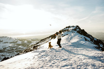 Woman and dog hiking on a snowy mountain