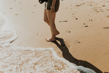 woman walking barefoot on a beach 