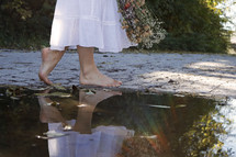 barefoot woman walking beside a puddle 