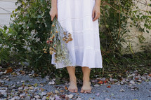 barefoot woman holding a bouquet of flowers 