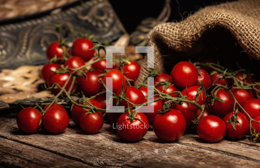 cherry tomatoes on wooden rustic table with jute sack.