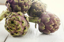 raw artichokes on white wooden table