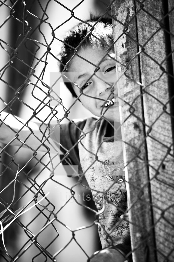 Child playing behind chain fence