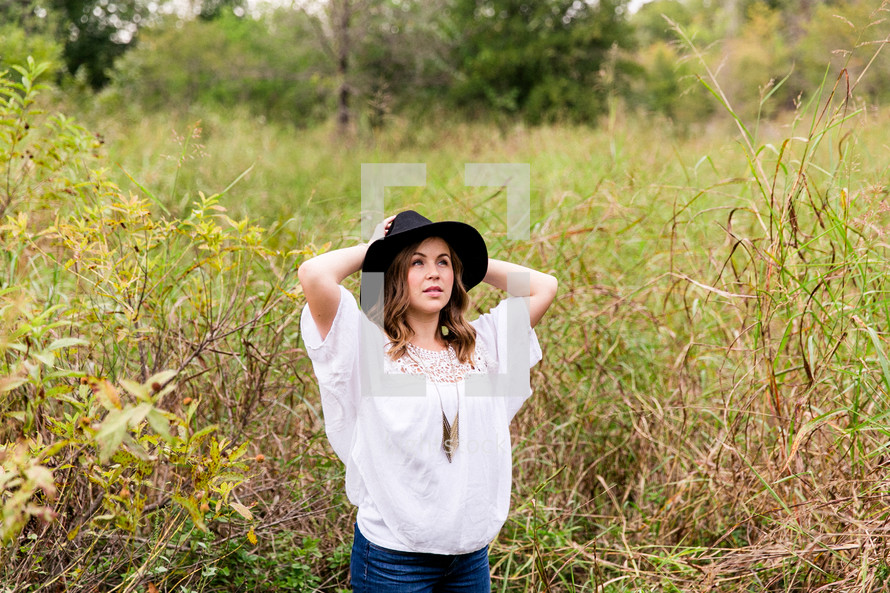 woman posing outdoors in a black hat 