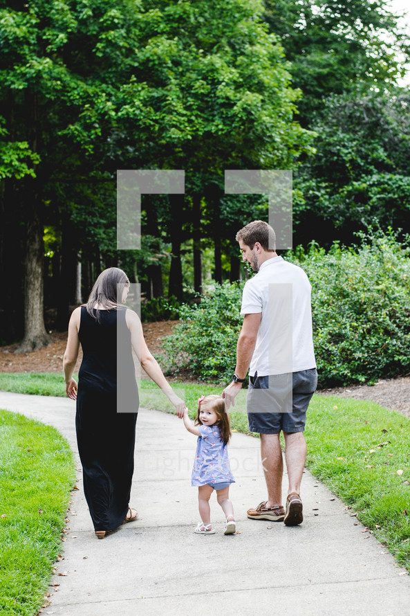 a family walking down a path holding hands 
