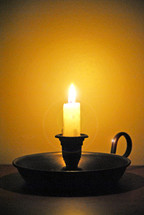 Lighted candle in candlestick.