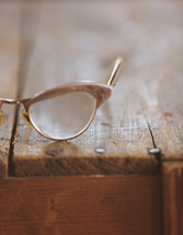 Eye glasses on a rugged wooden table.