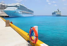 Cruise ships docked at a pier in a blue ocean.