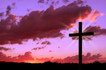 Silhouette of a cross against a sunset.