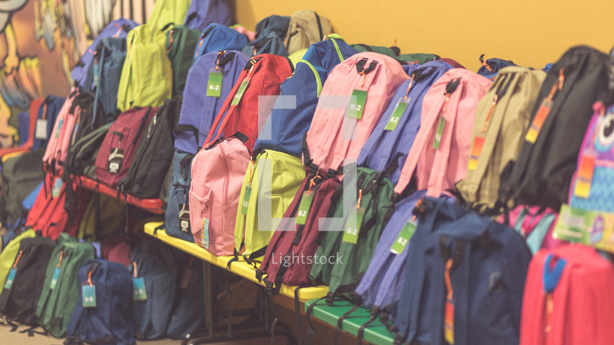 Benches full of colorful backpacks.