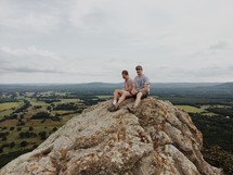 two men sitting on a rock peak