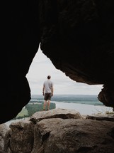 man standing on the edge of a mountain cave 