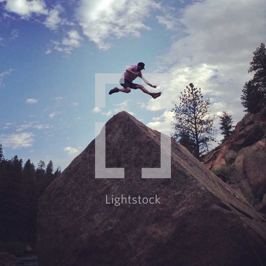 man leaping over a rock 