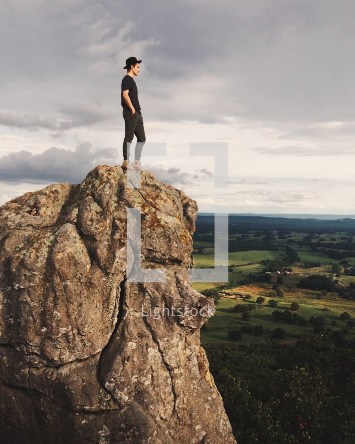 man standing at the edge of a mountain peak 