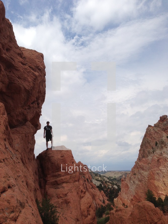 Silhouette of a man standing on a mountain ridge.