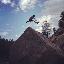 man leaping over a rock 