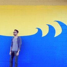 man standing in front of a wall with a wave painted on it