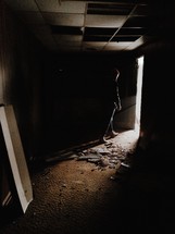 A man walking out of a dark, abandoned room.