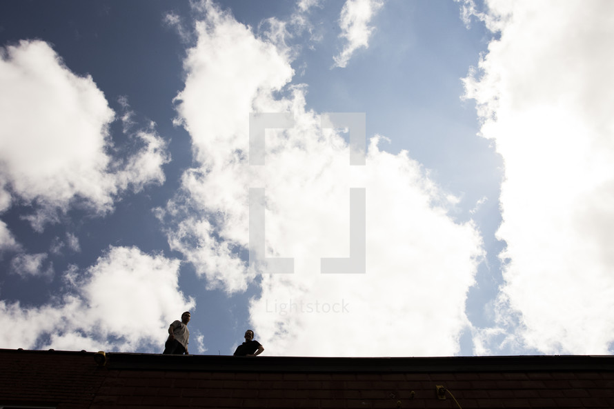 men standing on a roof under a blue sky