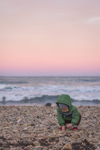 toddler playing with rocks on a beach 