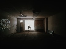 A silhouette of a person standing before a bright window in an empty room.