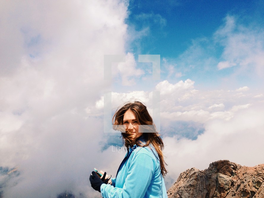 Woman in the clouds on a mountaintop.