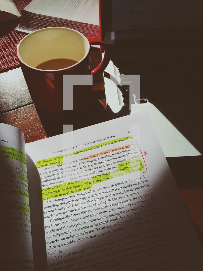 highlighted book, coffee mug, and laptop 