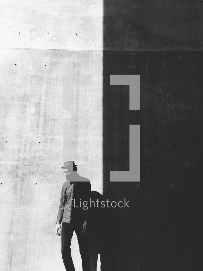 man and his shadow on a black and white wall 