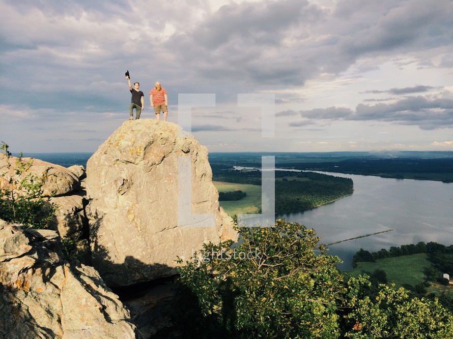 two men standing on a mountain peak 