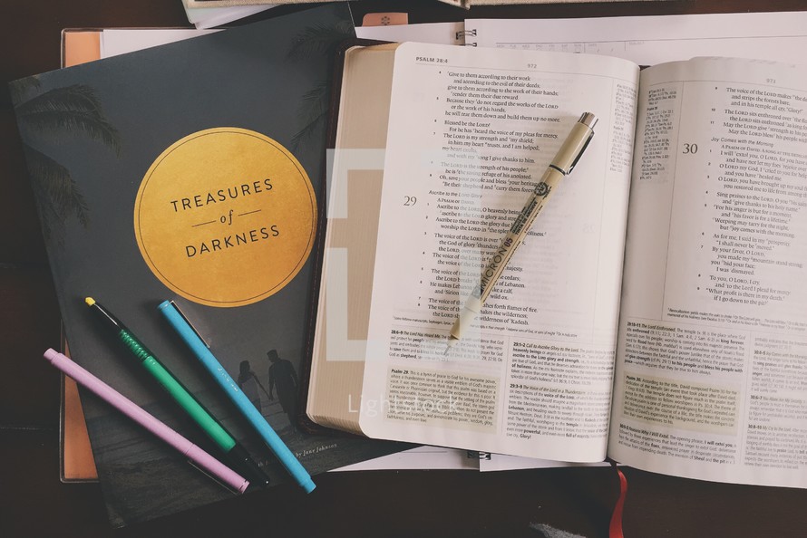 Treasures of darkness book, pens, and open Bible 