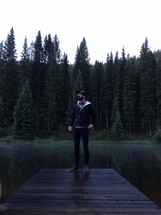 man standing on a pier at a lake
