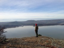 man standing at the edge of a mountain top looking out over a lake