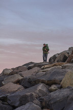 father and son on rocks near a beach 