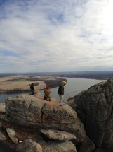 men standing on top of a rocky ledge looking out over a river
