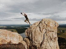 man leaping from one rock to another 