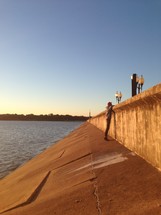 Man standing on a levee looking at street level.
