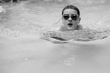Woman with goggles swimming in pool water.