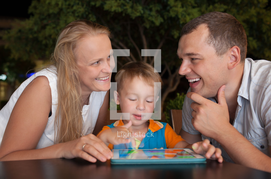 Happy family with tablet PC outdoor in the evening