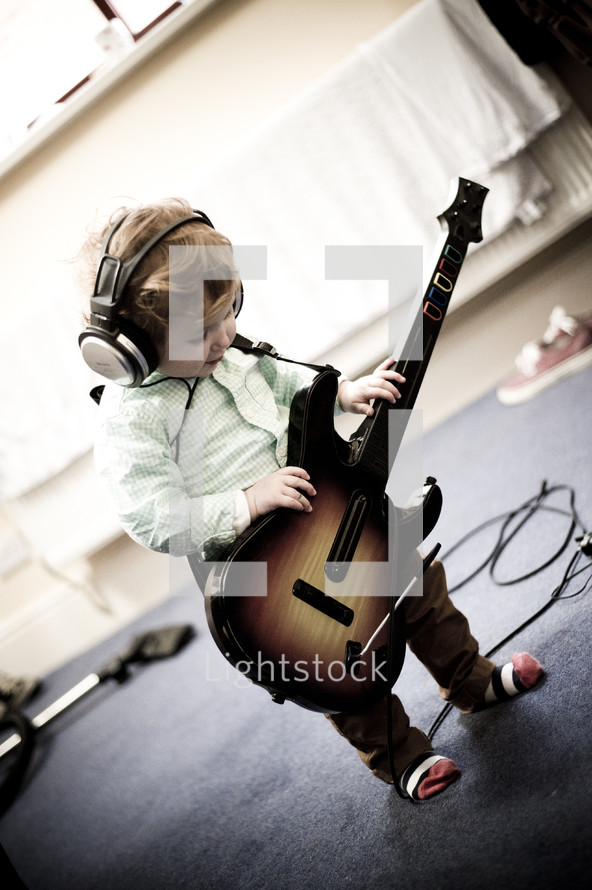 toddler boy with headphones and a guitar