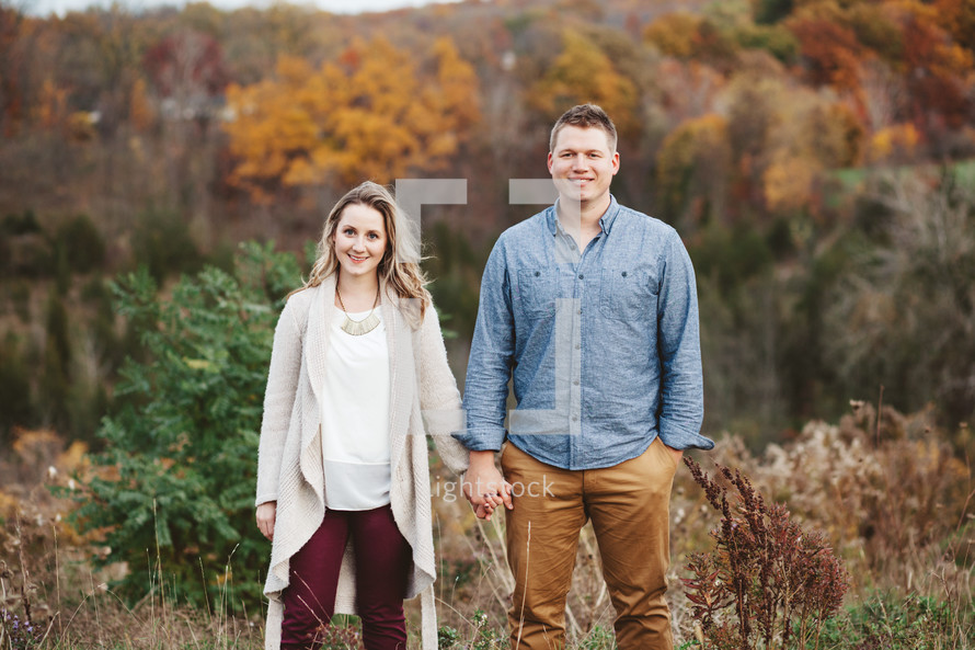couple holding hands outdoors in fall 