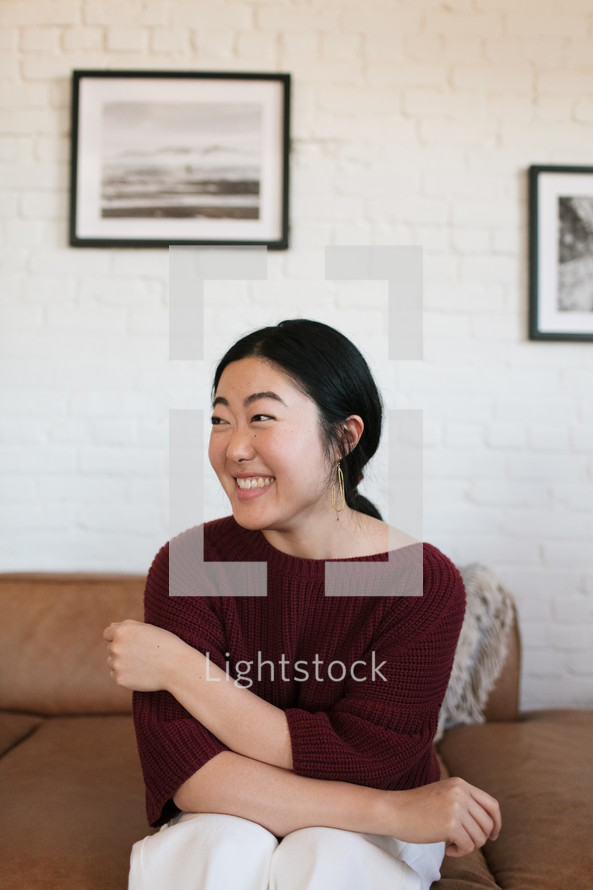 a smiling woman sitting on a couch 
