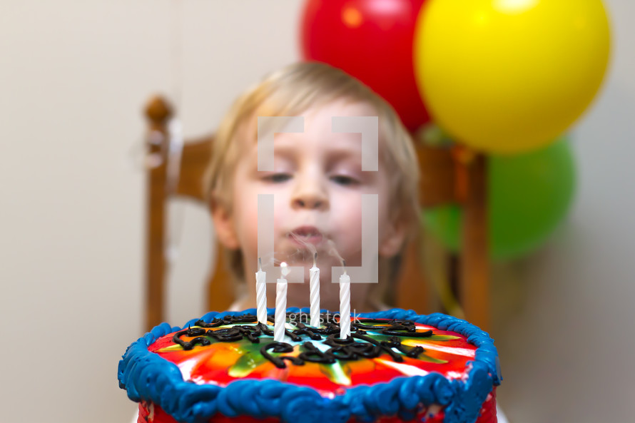 Child blowing out candles on a birthday cake.