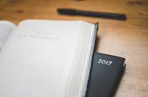 A bible open to the new testaments sits next to a 2017 diary on a desk